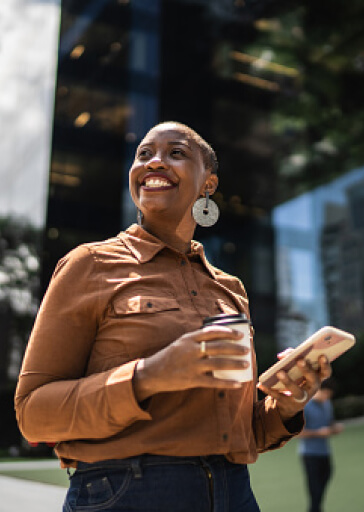 Smiling woman walking and using mobile phone