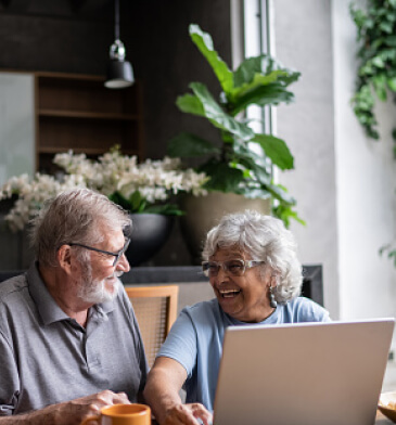 Mature couple laughing while using laptop
