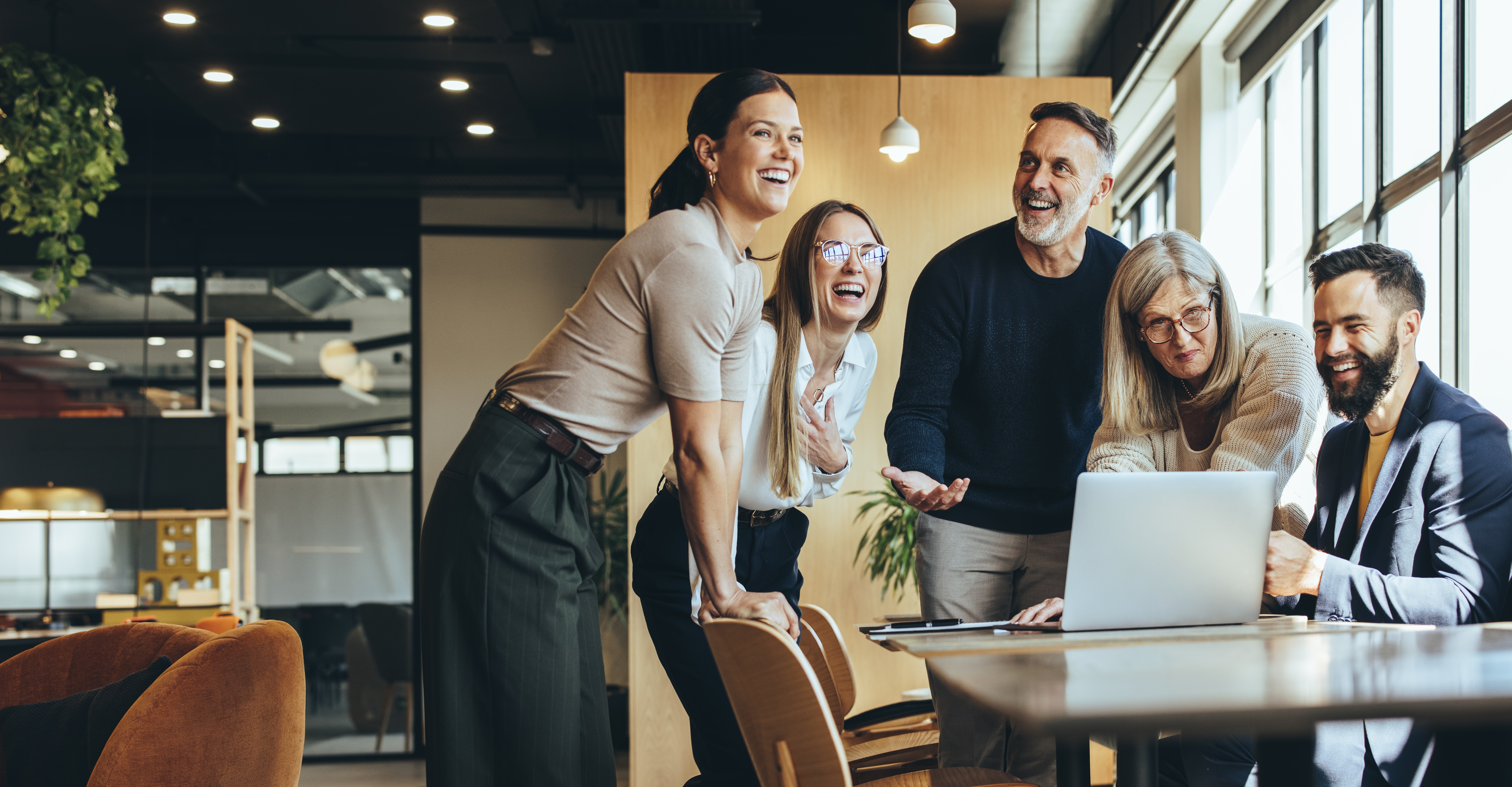 people around a laptop laughing